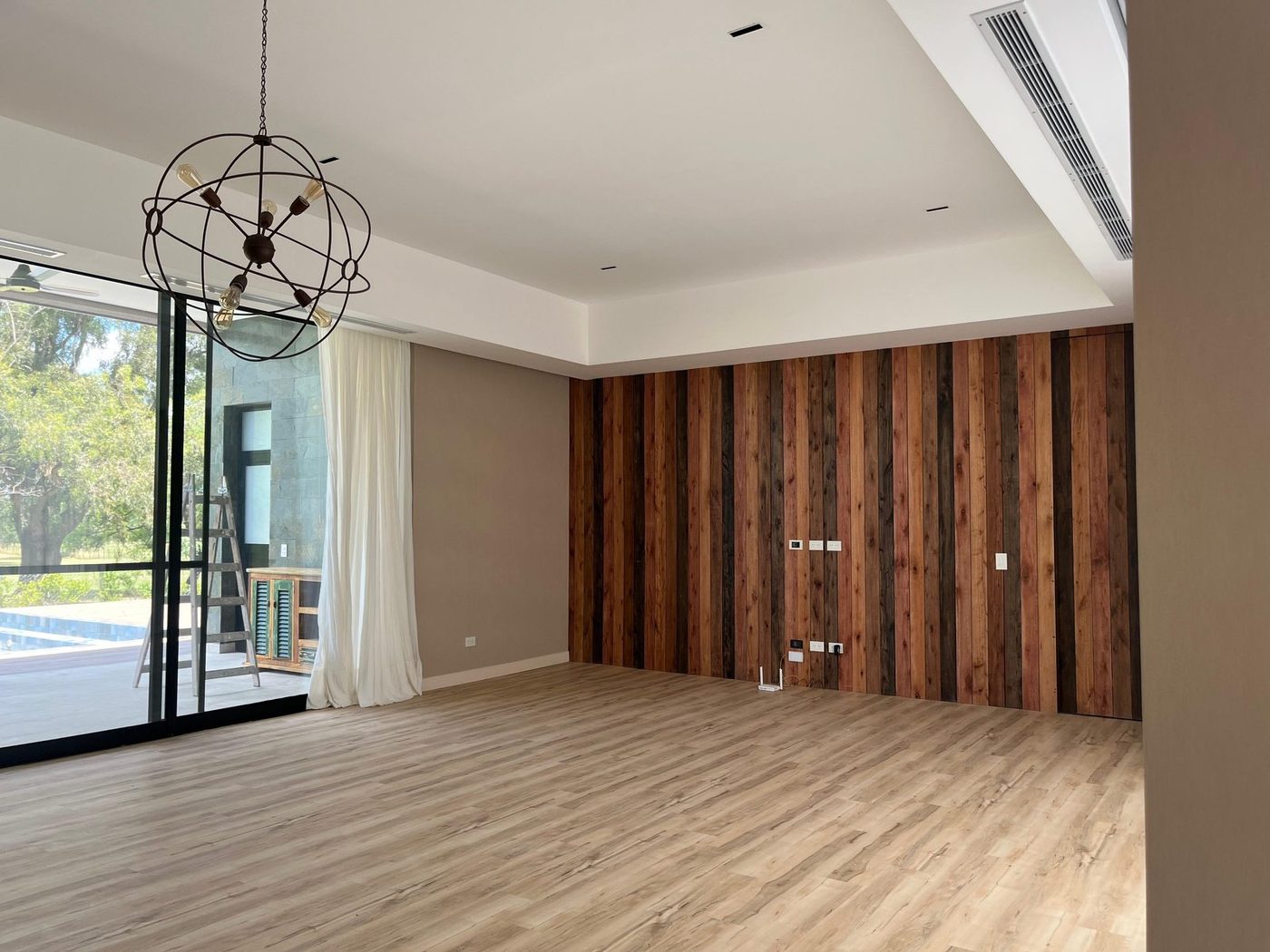 Living de doble altura con muro de madera y luz natural